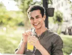 man smiling with headphones drinking lemonade